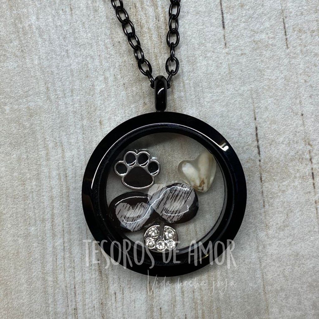 Relicario negro con cenizas figura infinito, diente figura corazón y dos piezas metálicas plateadas (letra “c” y huella negra de perrito)